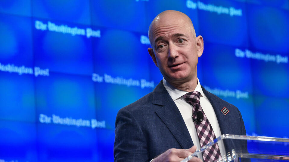 Jeff Bezos in front of a screen with the Washington Post logo